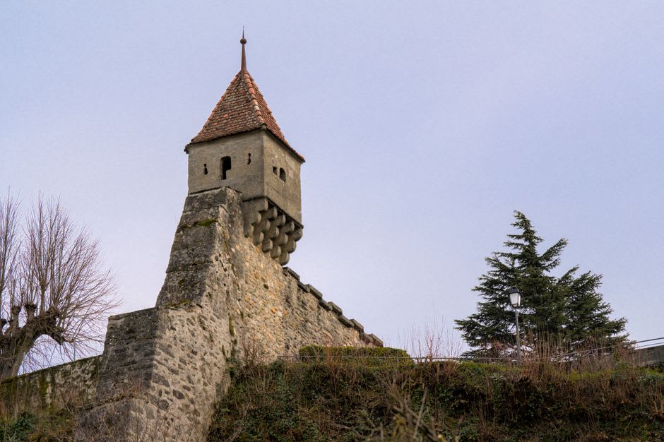 The narrow stone stairwell inside a tower of Château de Murol climbing toward daylight