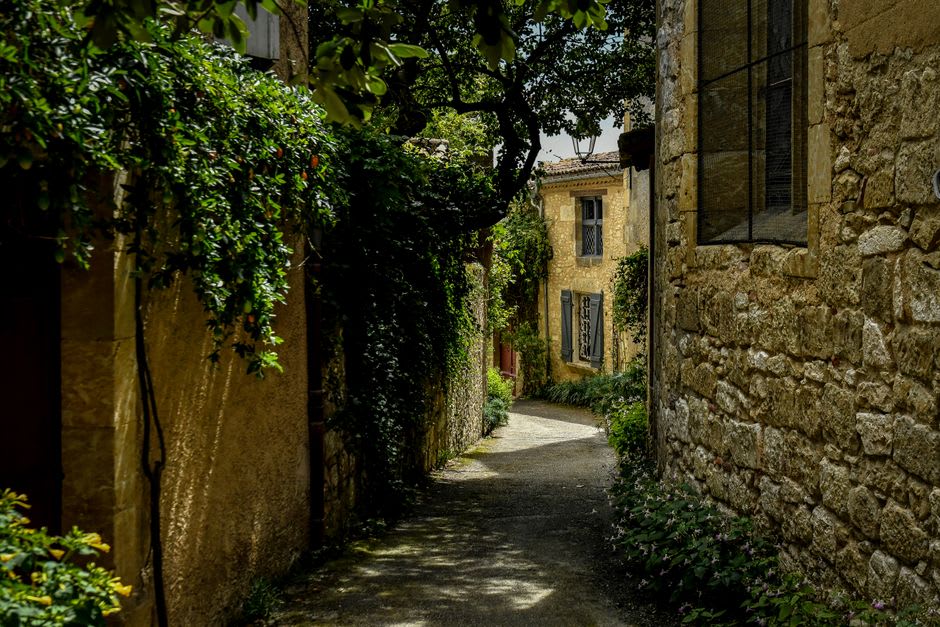 A narrow stone street inside Nozeroy's ramparts lined with tall medieval houses and shuttered windows