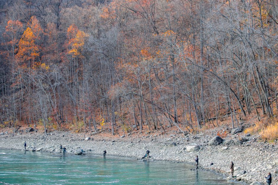 The clear green water of the Loue river running past Ornans with fishermen visible along the bank