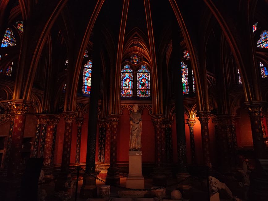 The stained glass windows of the Sainte-Chapelle in Riom glowing with color against the dark stone interior