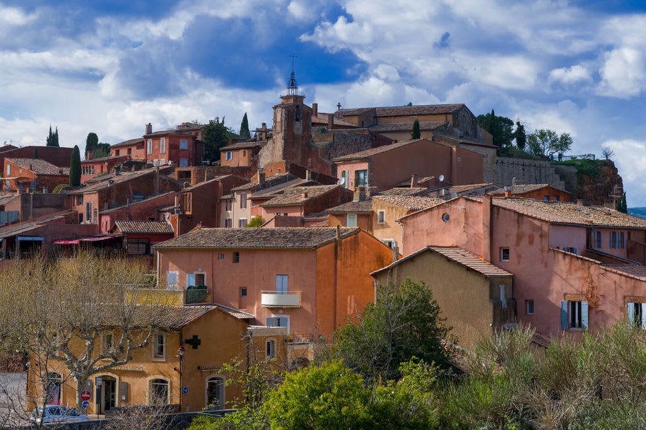 A narrow street in Roussillon lined with houses painted in matching shades of ochre and rust