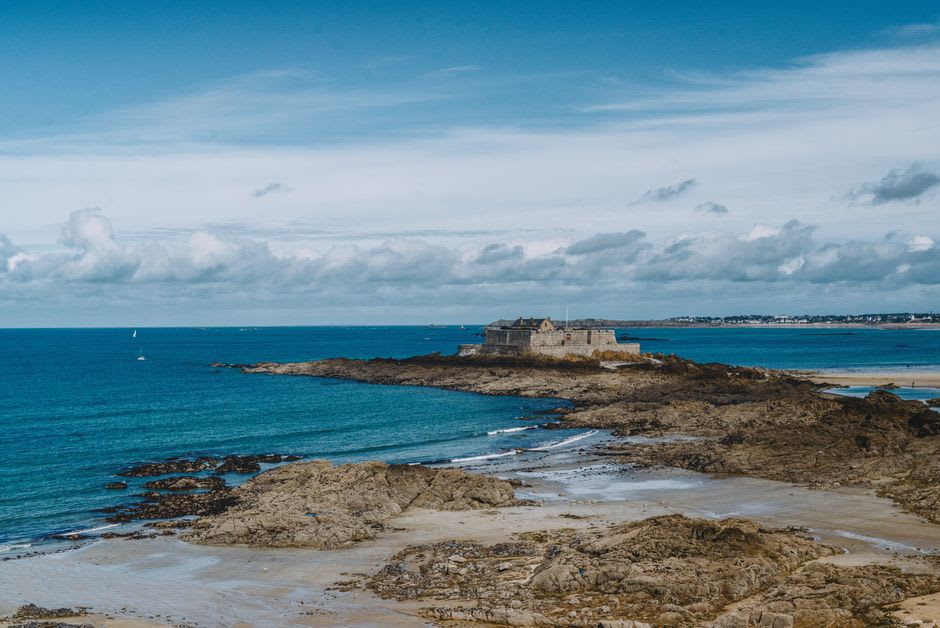 Fort National sitting on wet sand at low tide with Saint-Malo's ramparts visible across the bay