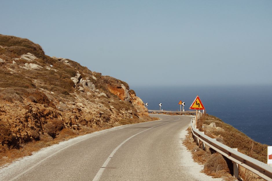 Winding cliffside road of the Corniche de l'Estérel with red volcanic rock dropping into the blue Mediterranean