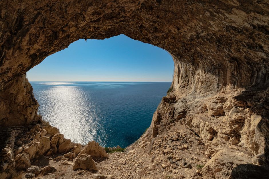 The natural rock arch above Speloncato framed against the late afternoon sky, with the Balagne coastline visible in the distance