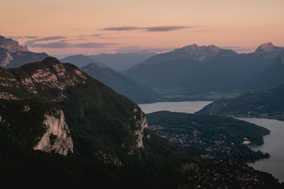 The stone facade of the old Benedictine priory at Talloires reflected in the still water of Lac d'Annecy at dusk