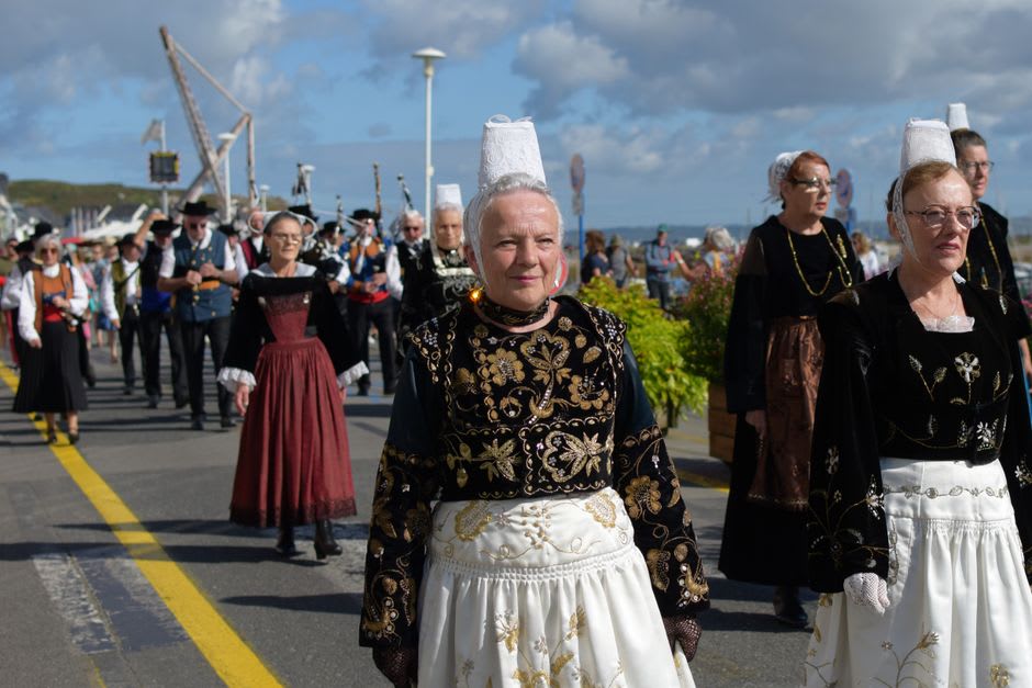 A traditional Breton pardon procession with embroidered banners passing through the streets of Tréguier
