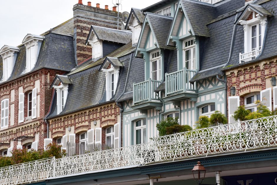 A row of pastel Belle Époque villas with turrets and wrought-iron balconies along a street in Vic-sur-Cère