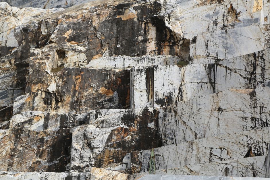 Massive cut blocks of dark volcanic stone stacked inside the disused Carrières de Volvic quarry