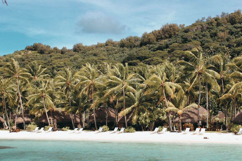 Small settlement on Mataiva with a white church and traditional houses along the lagoon shore, coconut palms framing the scene