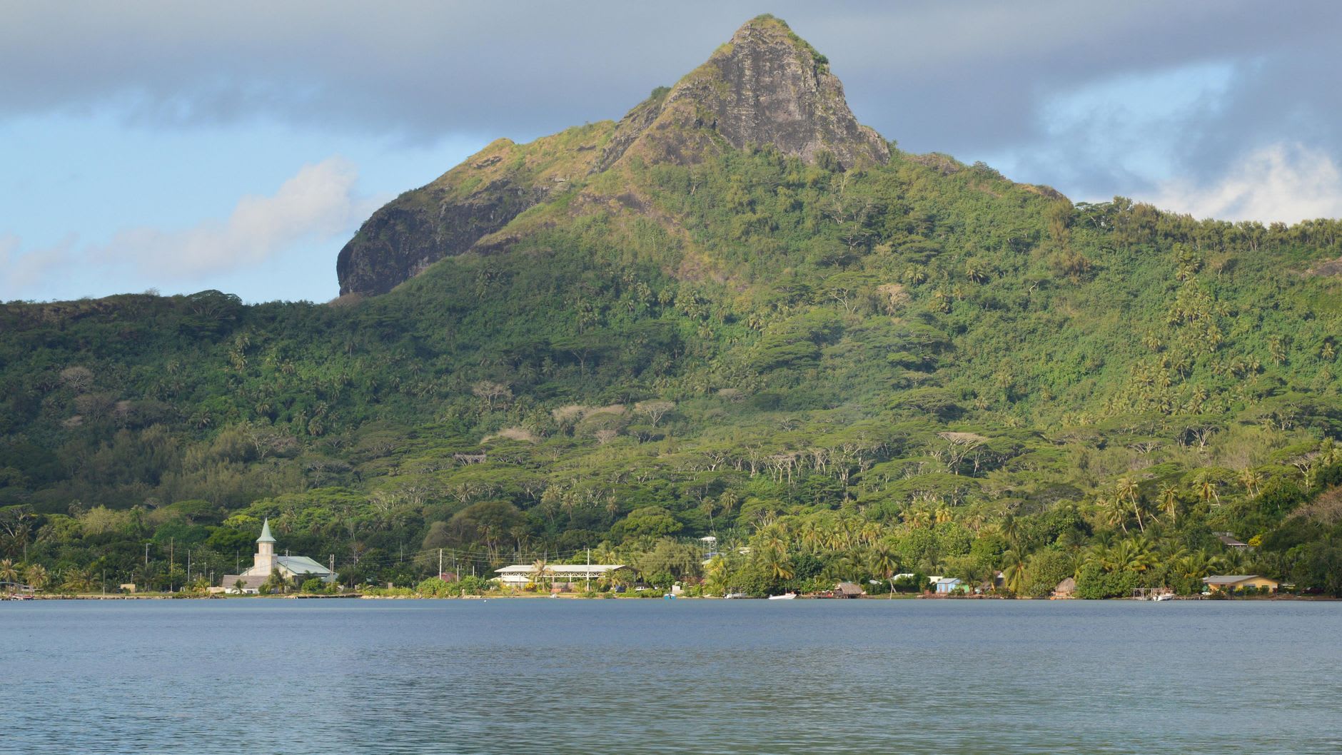 Valle Hakaui en Nuku Hiva, una catedral de acantilados verdes verticales que se estrechan hacia la cascada Vaipo visible en la lejanía, la luz de la mañana captando la niebla de las cascadas