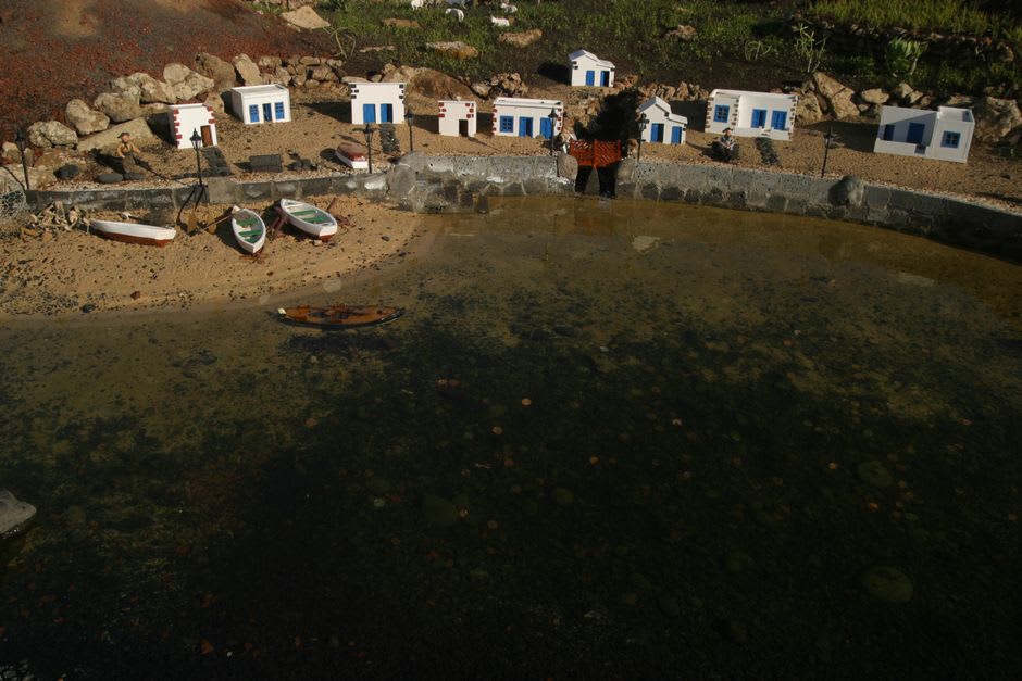 The volcanic pinnacles of Ua Pou rising behind the harbor village of Hakahau, fishing boats moored in the foreground