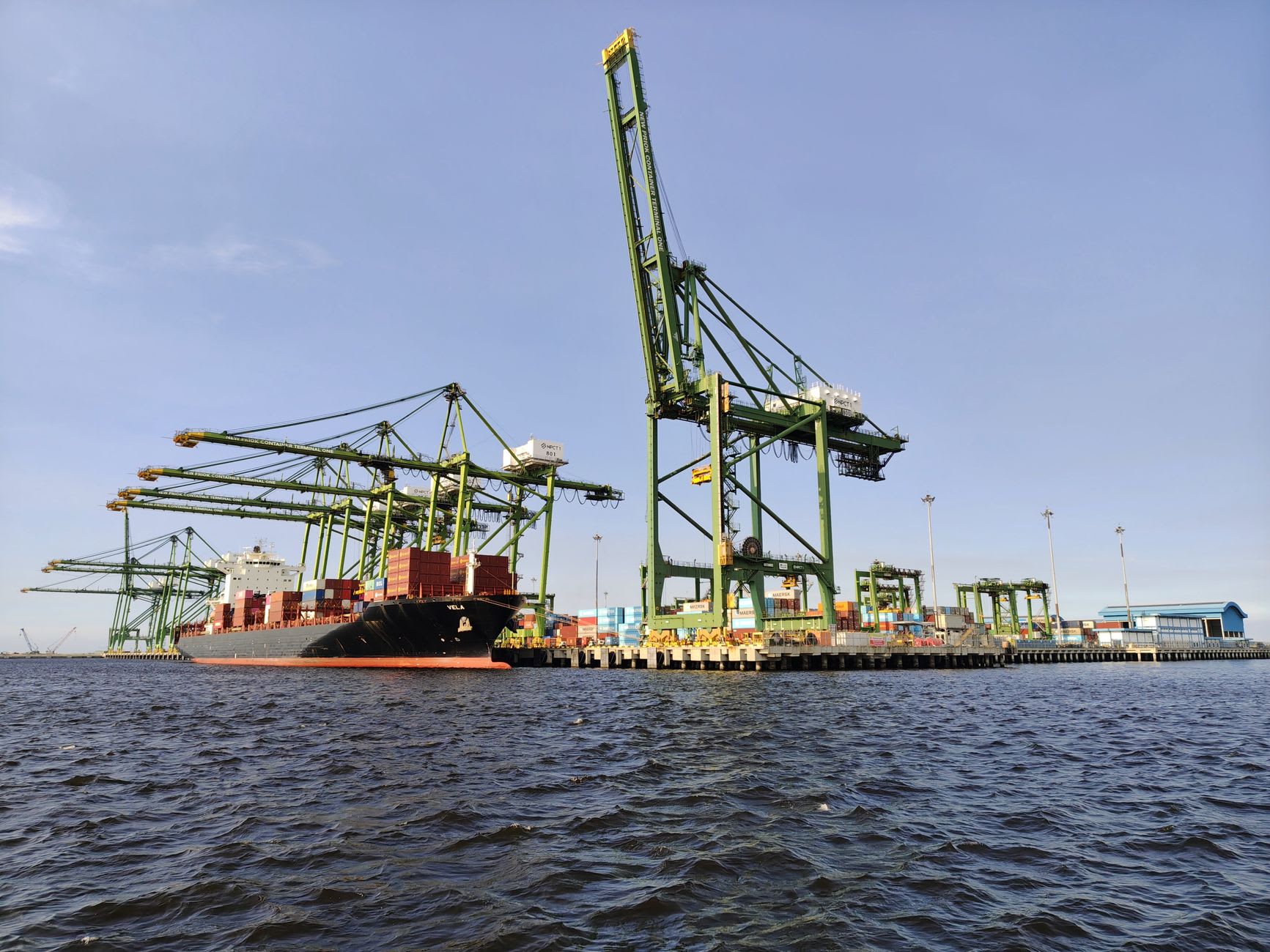 Pélicans et pirogues de pêche le long du front de mer de Port-Gentil, la lagune s'étendant jusqu'à l'horizon à l'aube