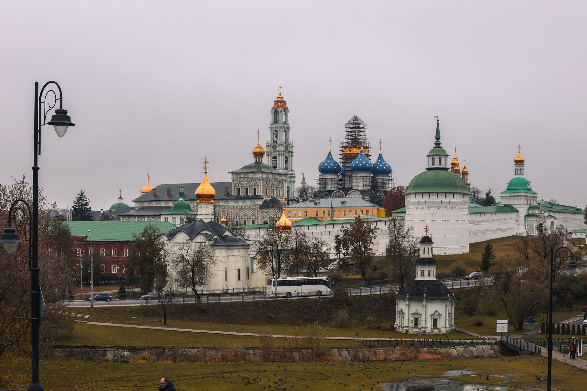 Pilgrims queuing at the Cathedral of the Trinity in the Trinity-Sergius Lavra, candle smoke rising in the dim interior