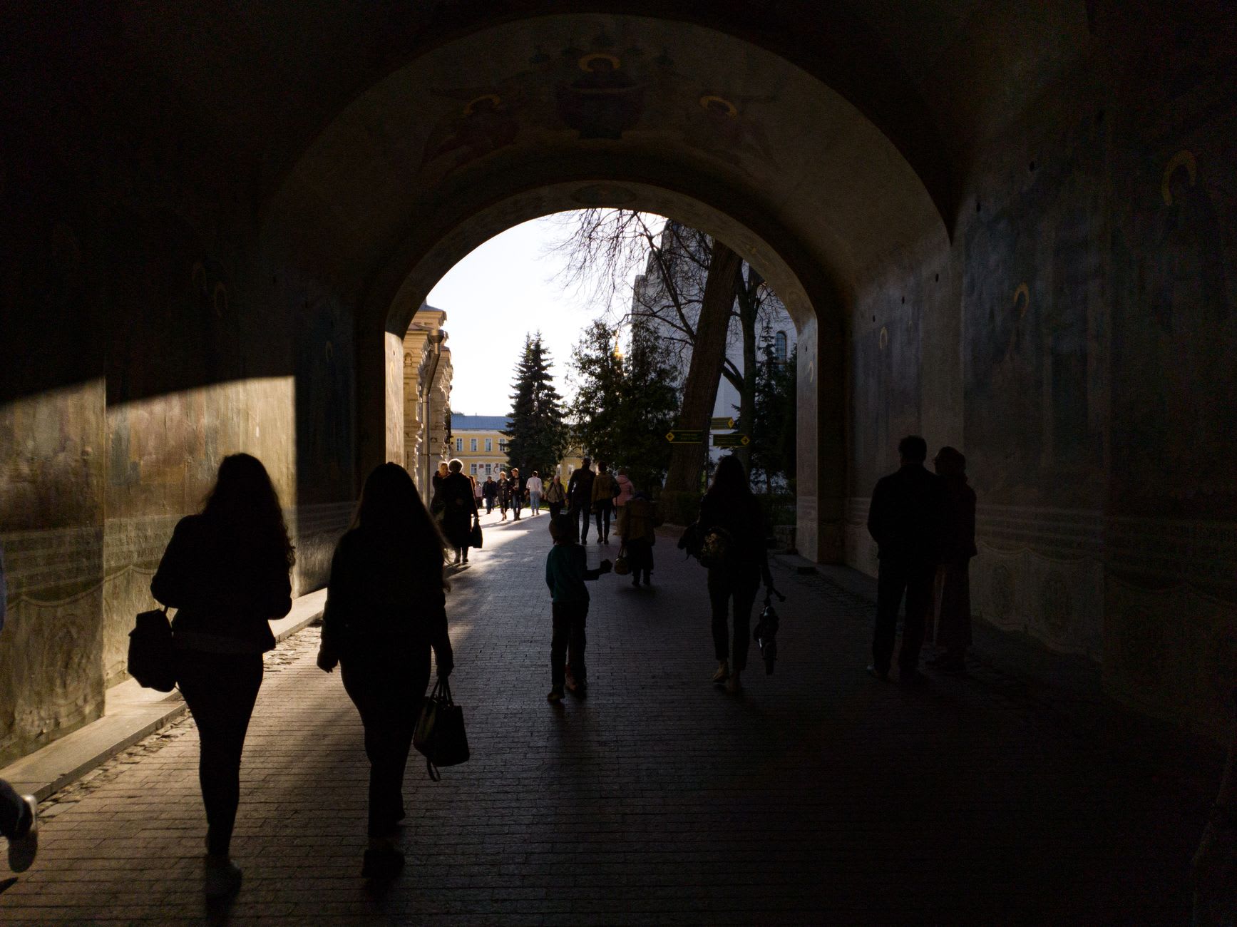 Monks walking the cobbled paths of the Trinity-Sergius Lavra at twilight, oil lanterns lit along the walls