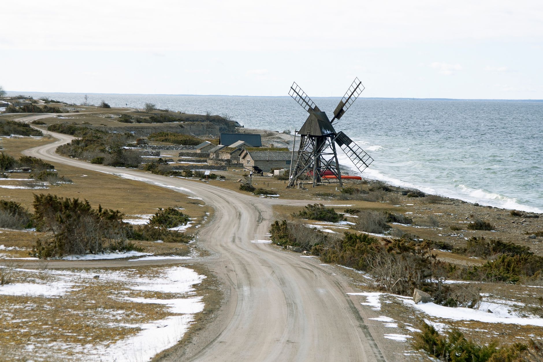 El museo al aire libre Bungemuseet con edificios de granjas tradicionales de Gotland y un molino de viento en una mañana de septiembre, hierba baja y cielo despejado
