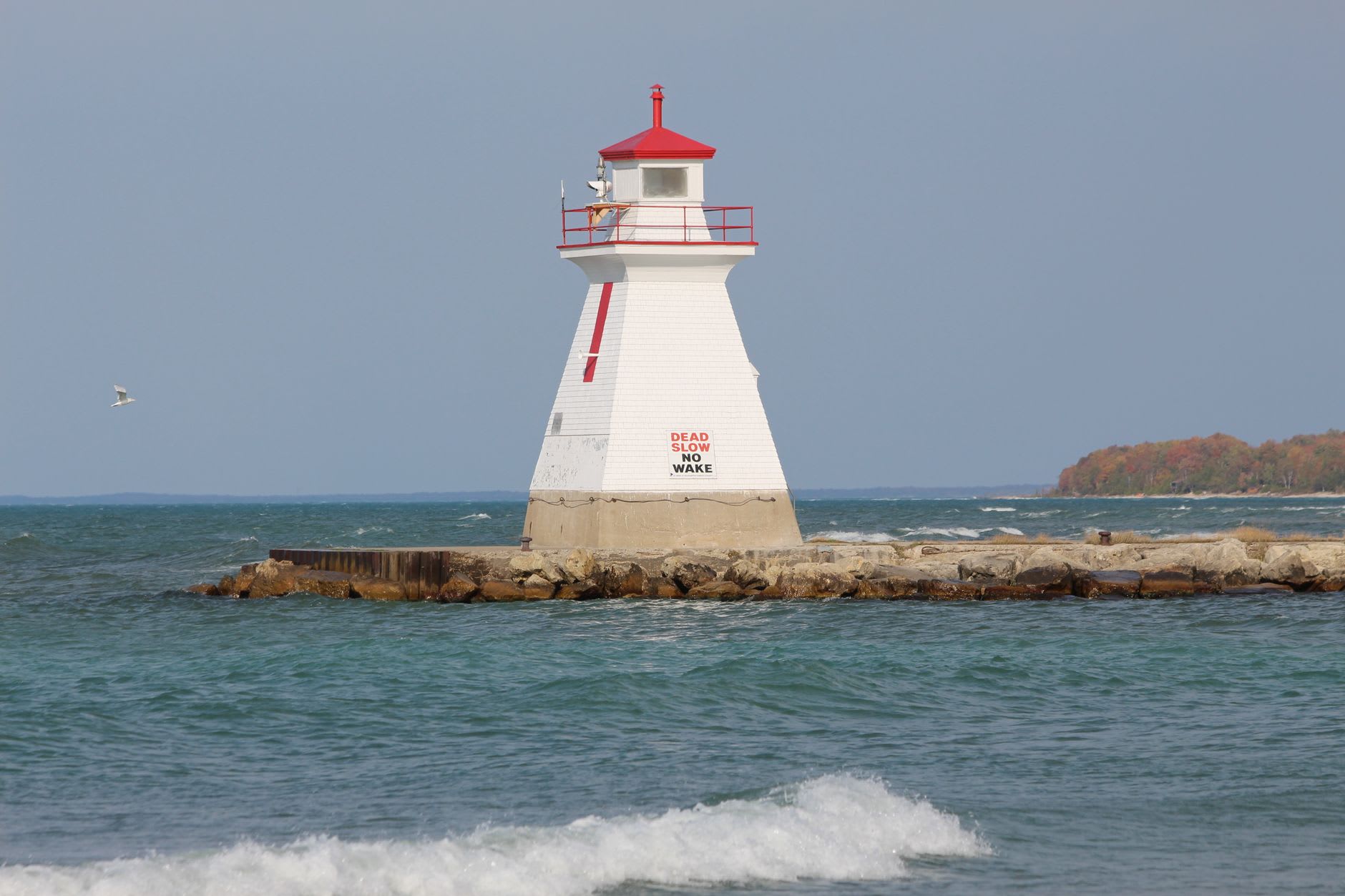 Le lagon protégé de Presque Isle par un calme matin d'automne, un grand héron bleu immobile dans les eaux peu profondes, le ciel se reflétant parfaitement dans l'eau quiete