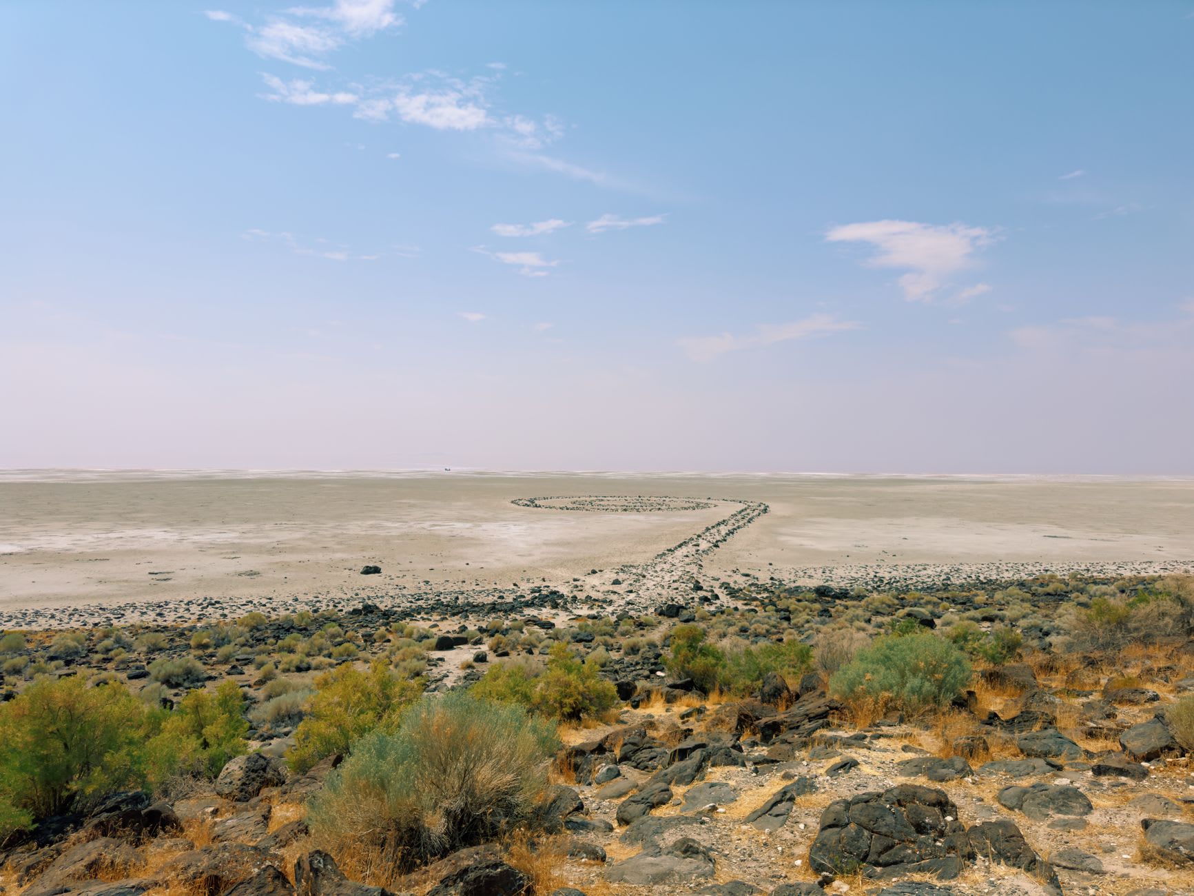 The volcanic landscape around South Island in Lake Turkana, dark lava rock meeting jade water under a huge pale sky