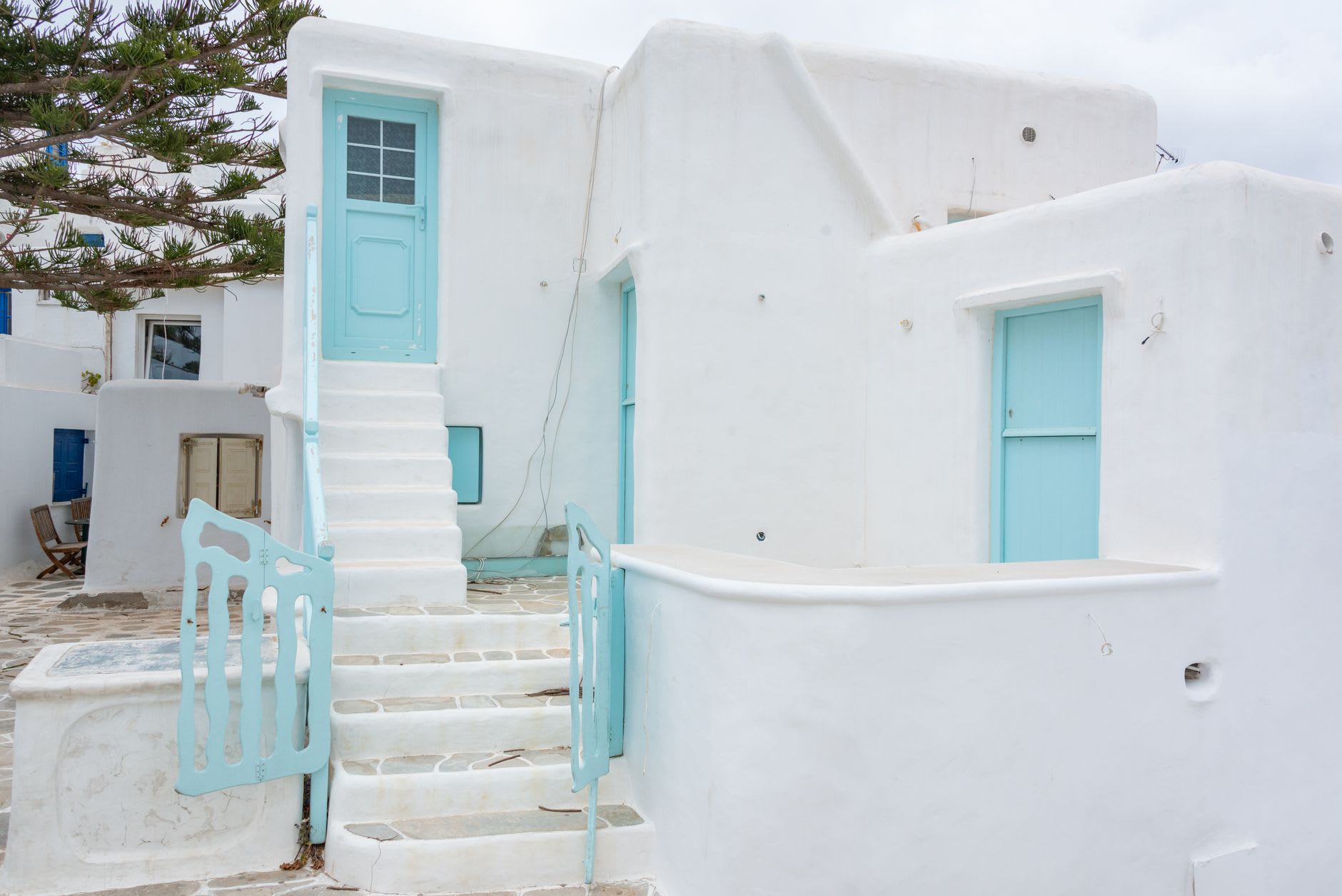 Whitewashed Cycladic buildings with blue shutters and bougainvillea in the lanes of Mykonos Town