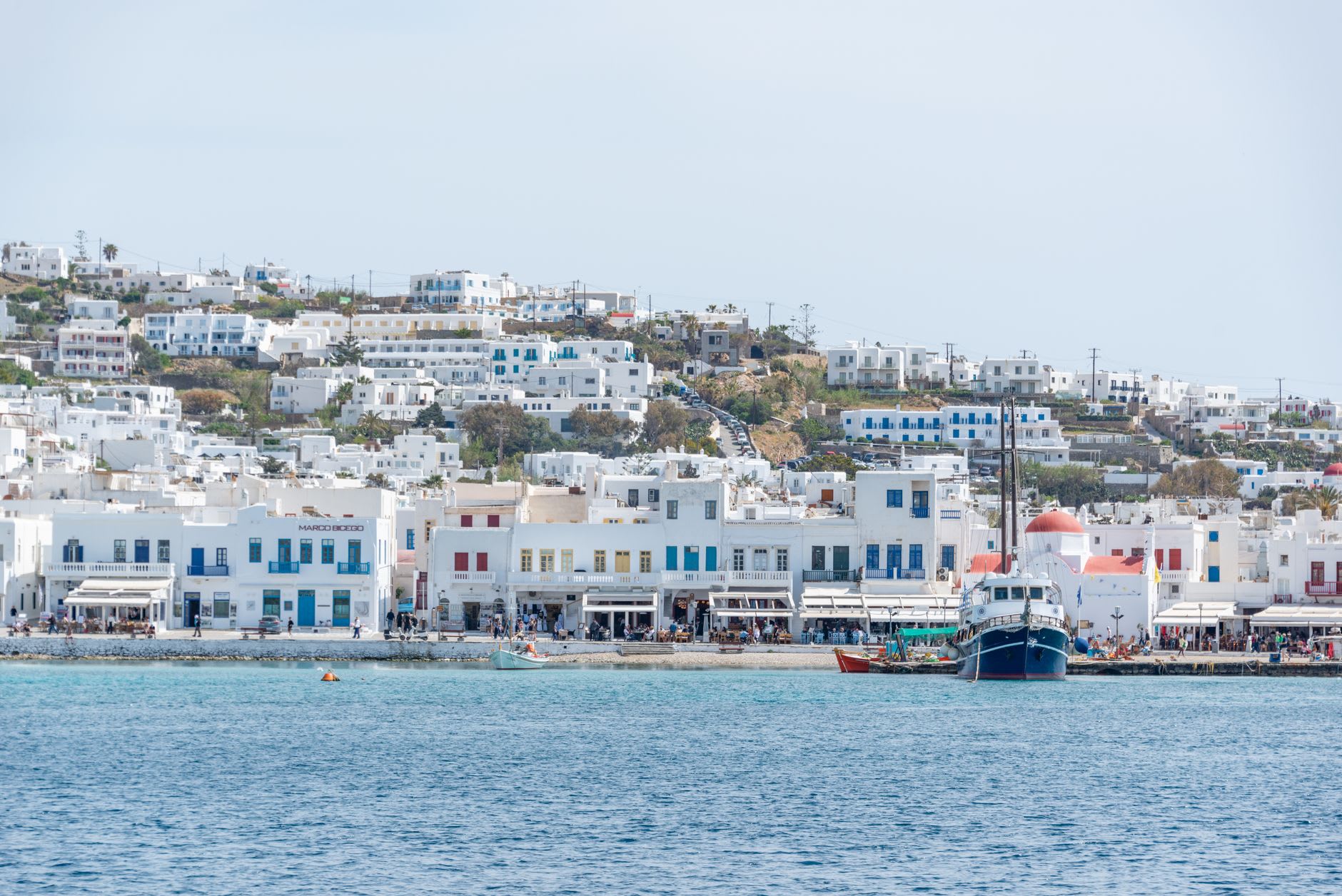 Mykonos Town harbor at dusk with colorful boats and whitewashed waterfront buildings reflecting on the water