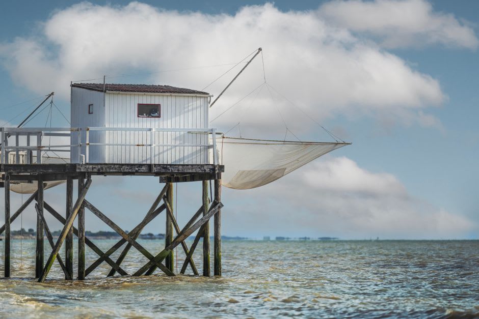 Wooden ajoupa fishing cabin standing on stilts in the shallow lagoon waters