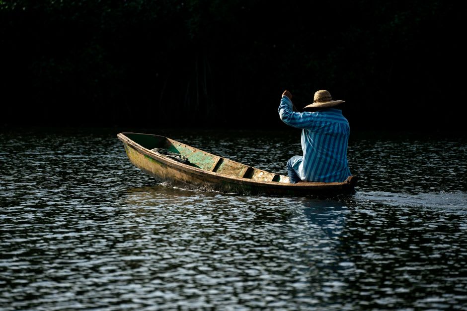 A wooden lancha boat drifting on the Río de la Pasión near Sayaxché at golden hour