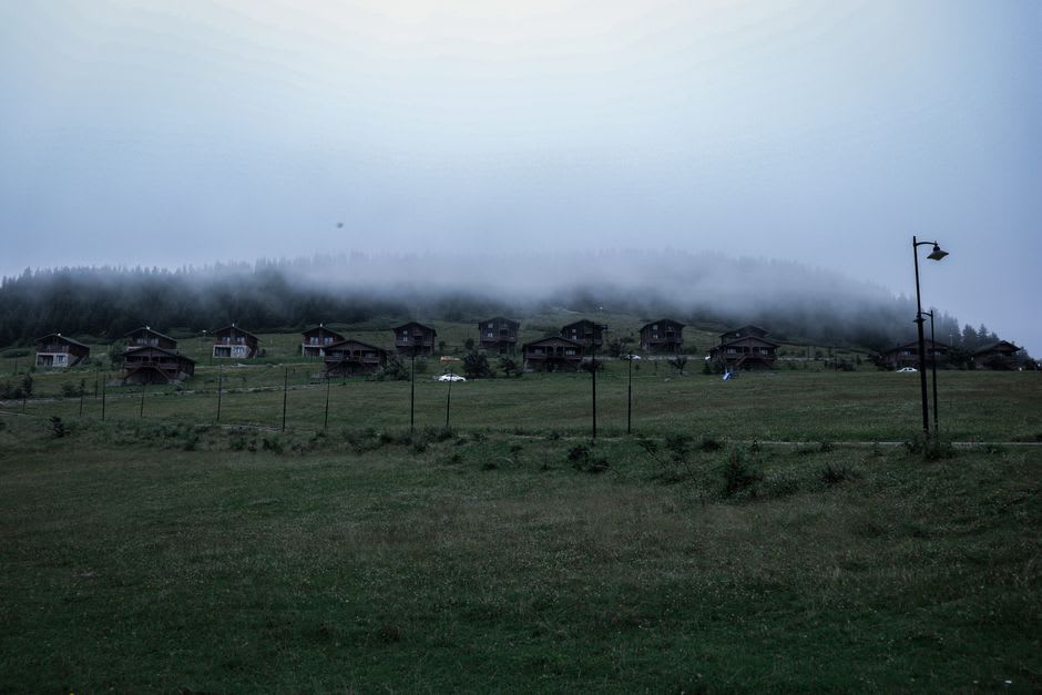 Wooden cabins overlooking the misty crater basin at dusk