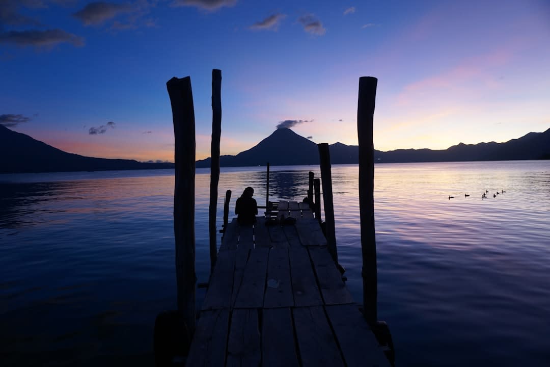 Sunset silhouette of volcanoes across Lake Atitlán seen from the Panajachel shoreline