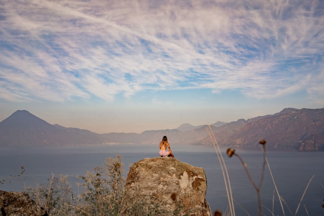 Swimmer jumping from a cliff platform into the clear turquoise water of Lake Atitlán