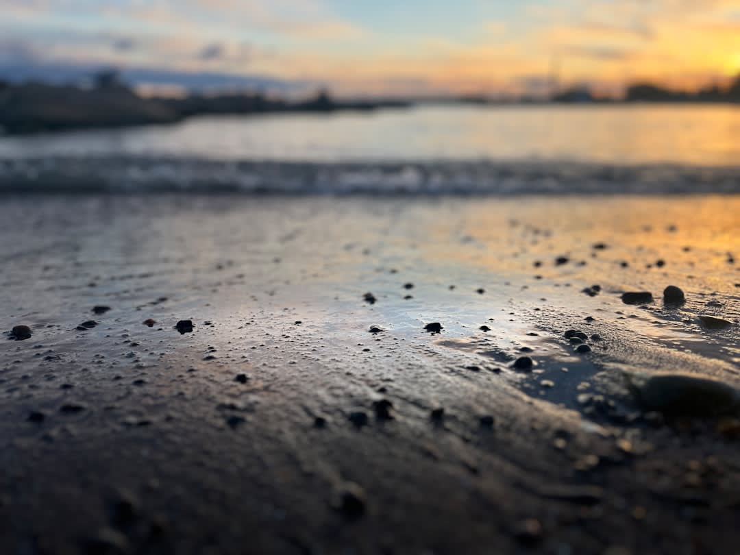 Coucher de soleil sur une plage de sable volcanique noir avec de petites vagues déferlant à Sipacate