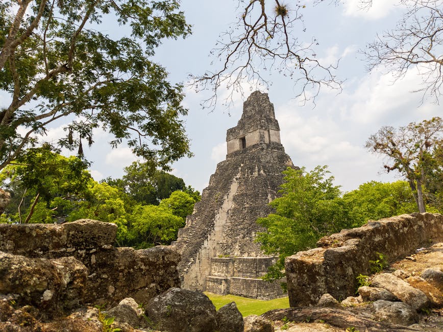 Ancient Maya temple rising above the jungle canopy in golden morning light