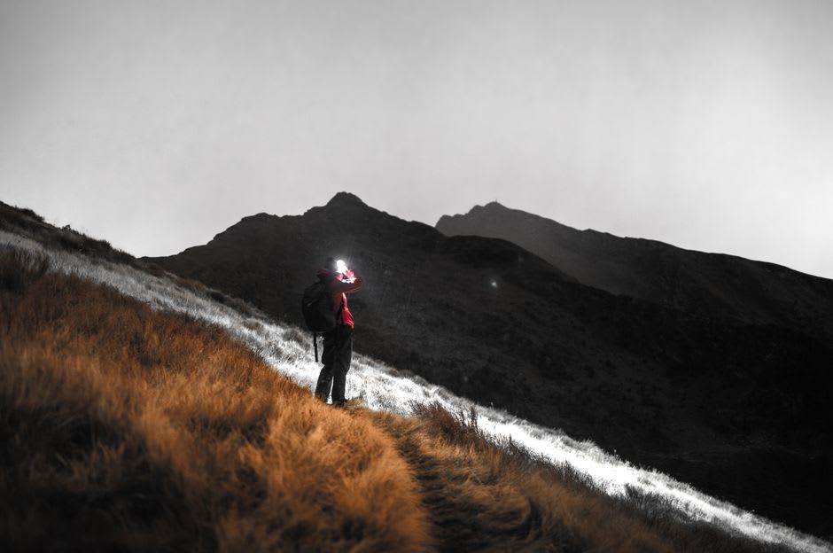 Randonneurs avec lampes frontales gravissant un sentier forestier obscur sur les pentes basses du Volcán de Agua avant l'aube