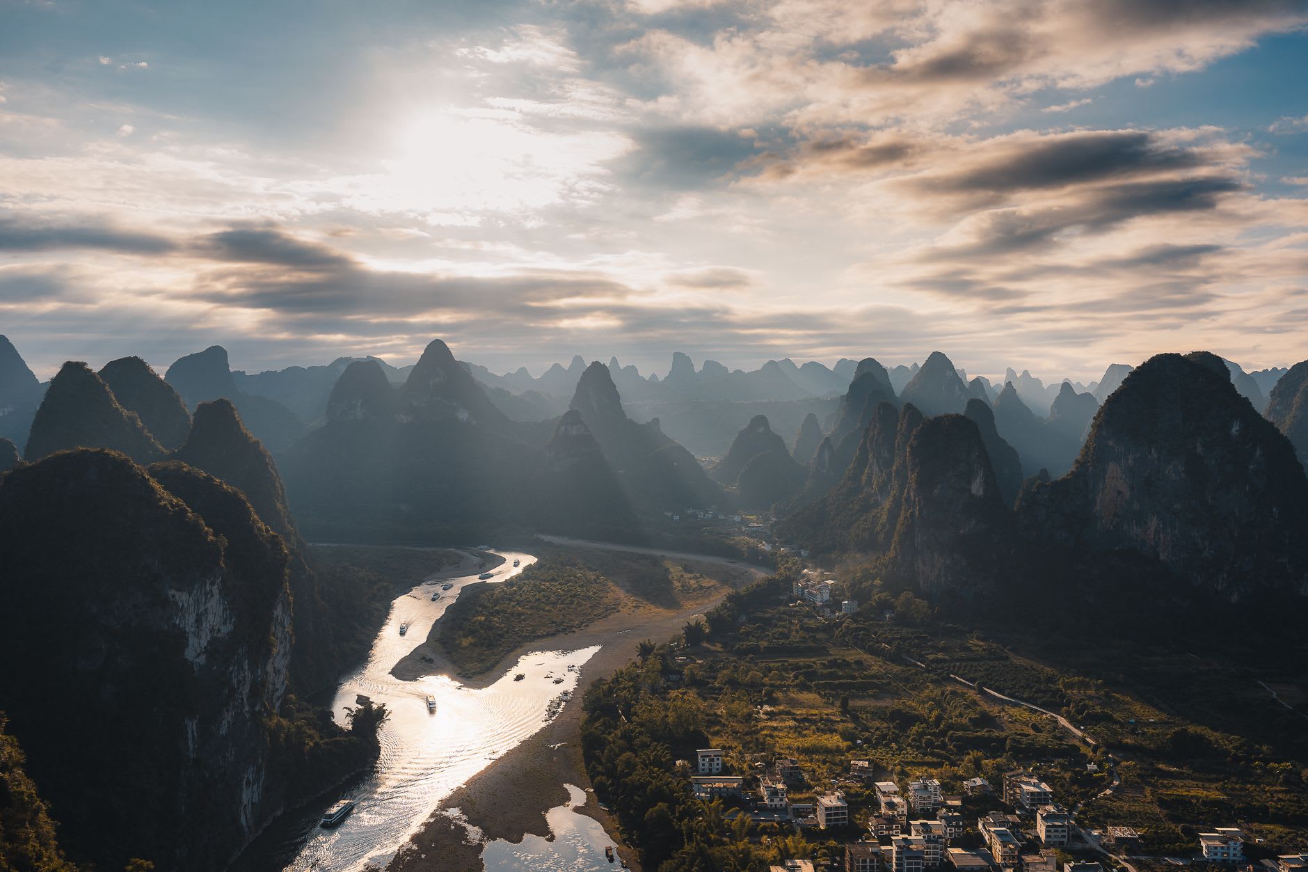 The Li River viewed from Fuli's wooden dock, karst peaks rising in the background with a small fishing boat passing in the morning mist