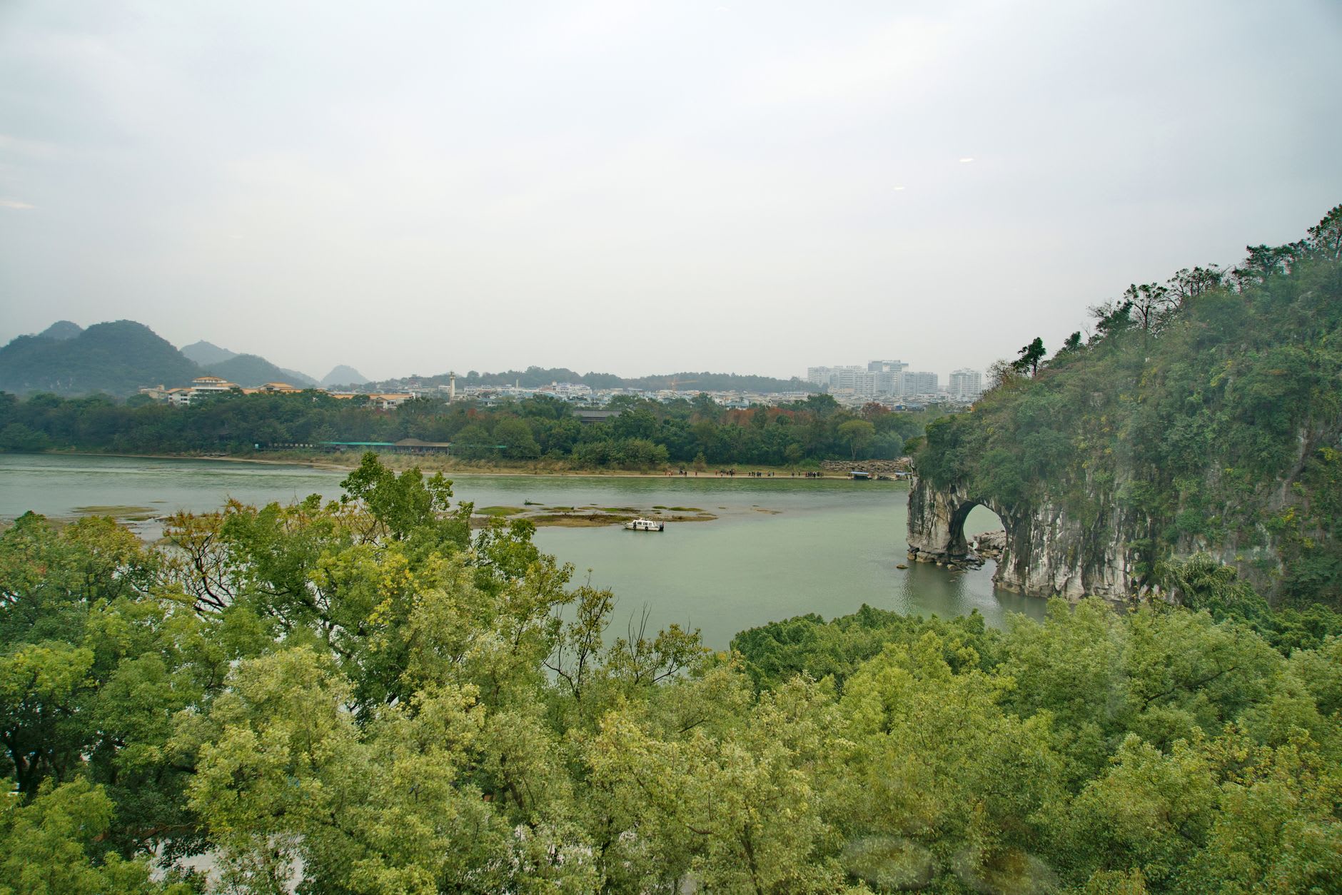 A simple village breakfast of rice congee and fried dough sticks on a low table at the foot of Xianggong Hill, karst peaks behind