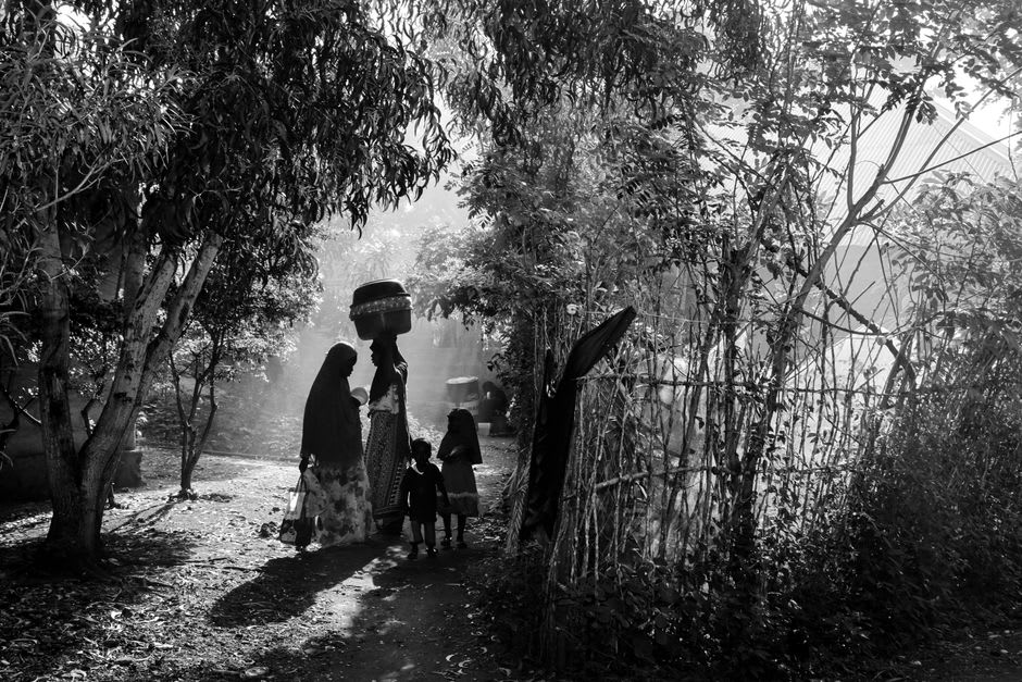 Bijagó women walking along a sandy path through the forest on Canhabaque Island