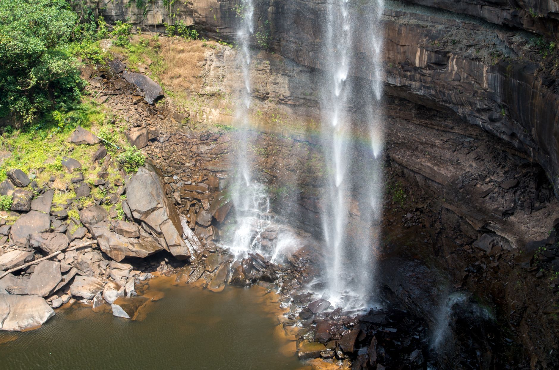 The middle terraces of Orinduik Falls, amber water pooling over orange jasper steps in brilliant afternoon light