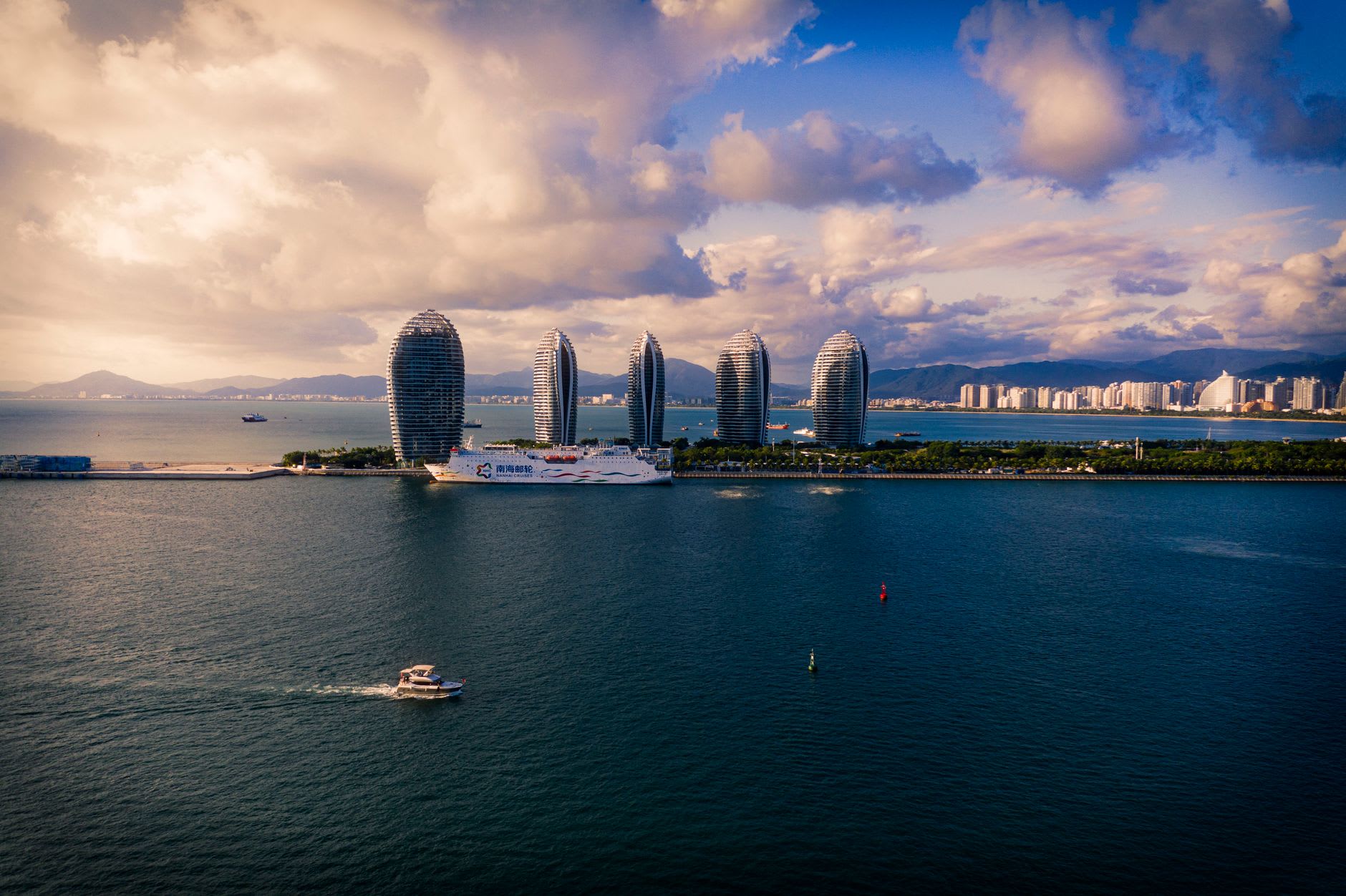 Qinglan Harbour near Wenchang, fishing boats moored at the quay and a floating seafood restaurant visible at the water's edge