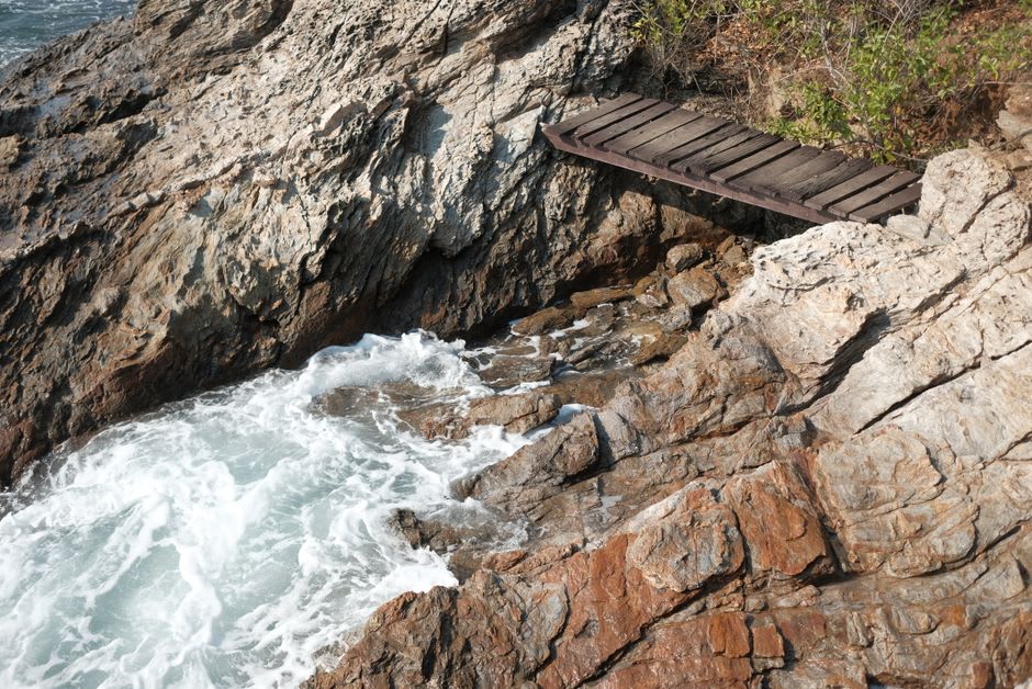 Wooden Lover's Bridge stretching between rocky outcrops with the sea below on Wuzhizhou Island