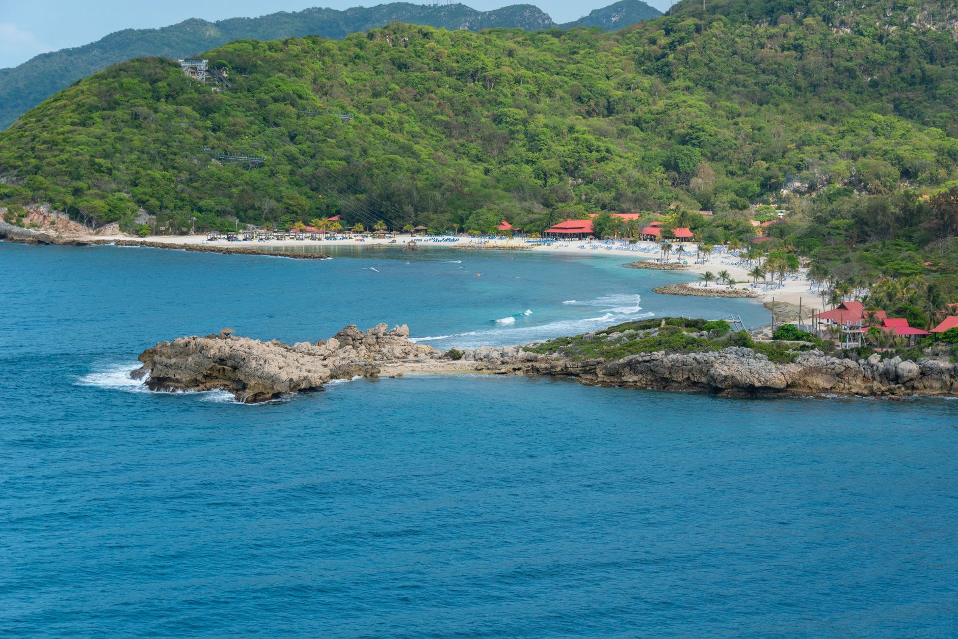A local fisherman's wooden boat with hand-painted decorations bobbing in the calm bay at Labadie, green hills behind