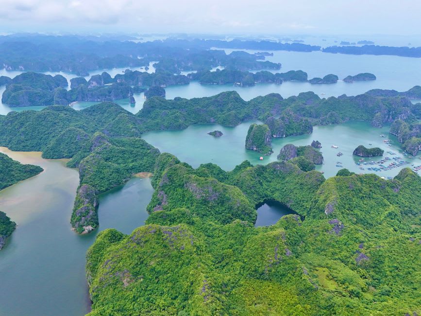 Limestone karst cliffs enclosing the sheltered lagoon of Ba Hang fishing village