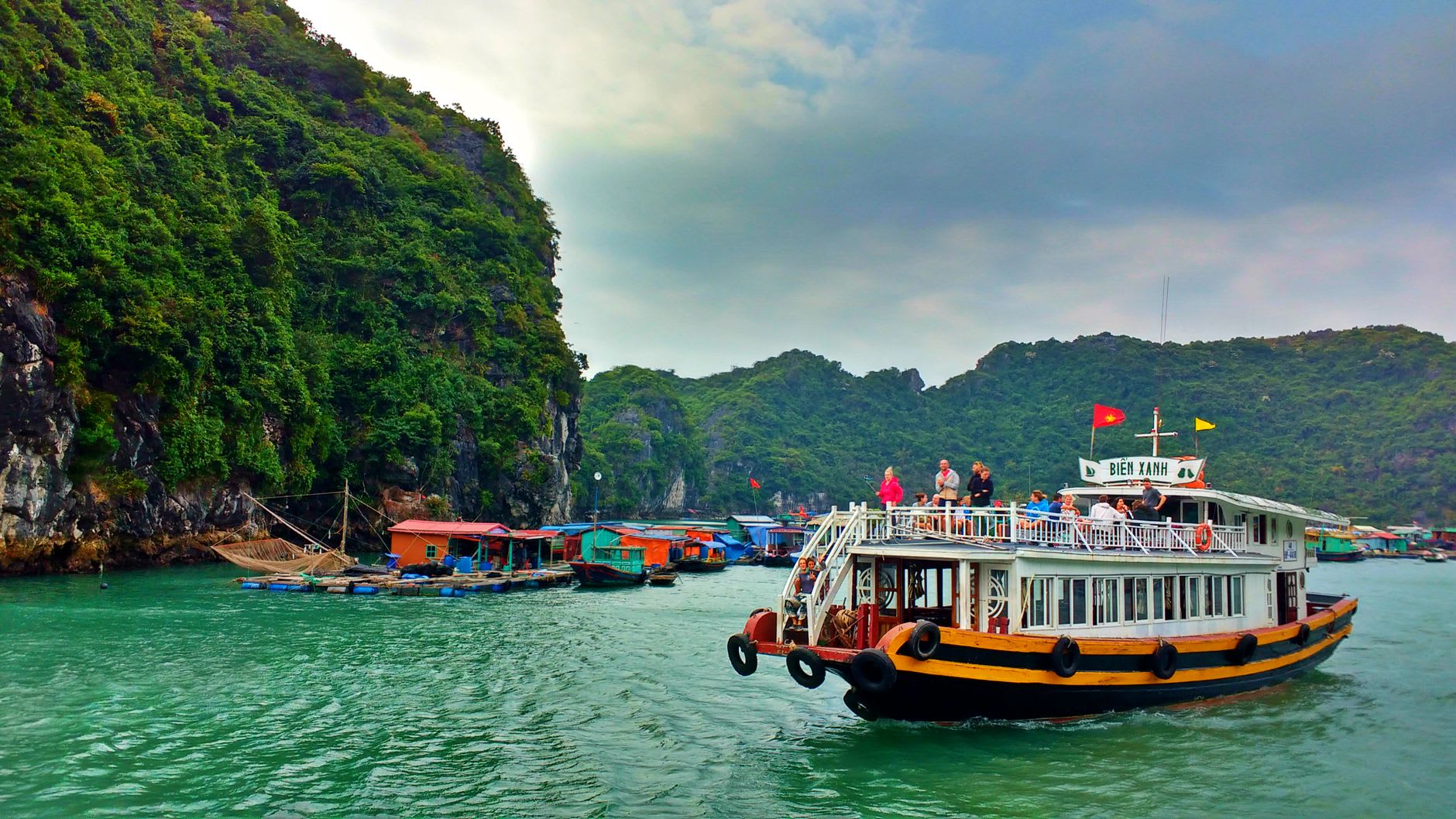 Pearl farming cages submerged below a floating platform at Vung Vieng, visible through the clear green water