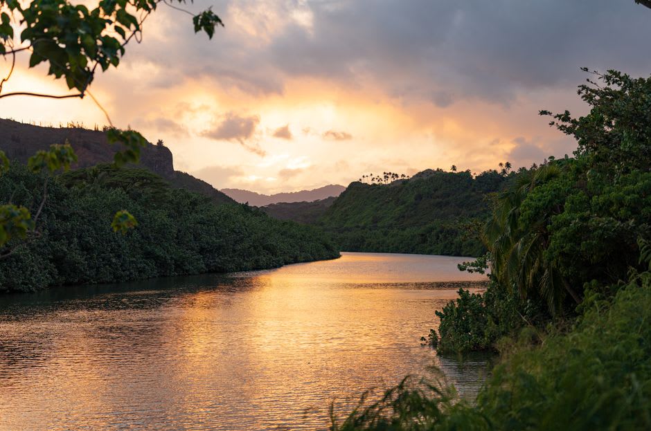 Uluwehi Falls, also known as Secret Falls, cascading into a swimming pool surrounded by lush volcanic rock and greenery