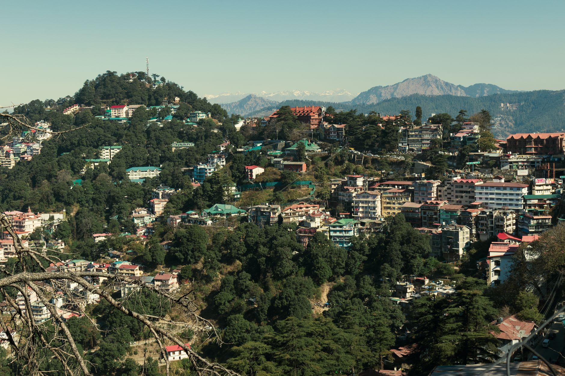 The narrow lanes and tiered buildings of Shimla's Lower Bazaar draped in coloured cloth and shop signs on a misty mountain morning