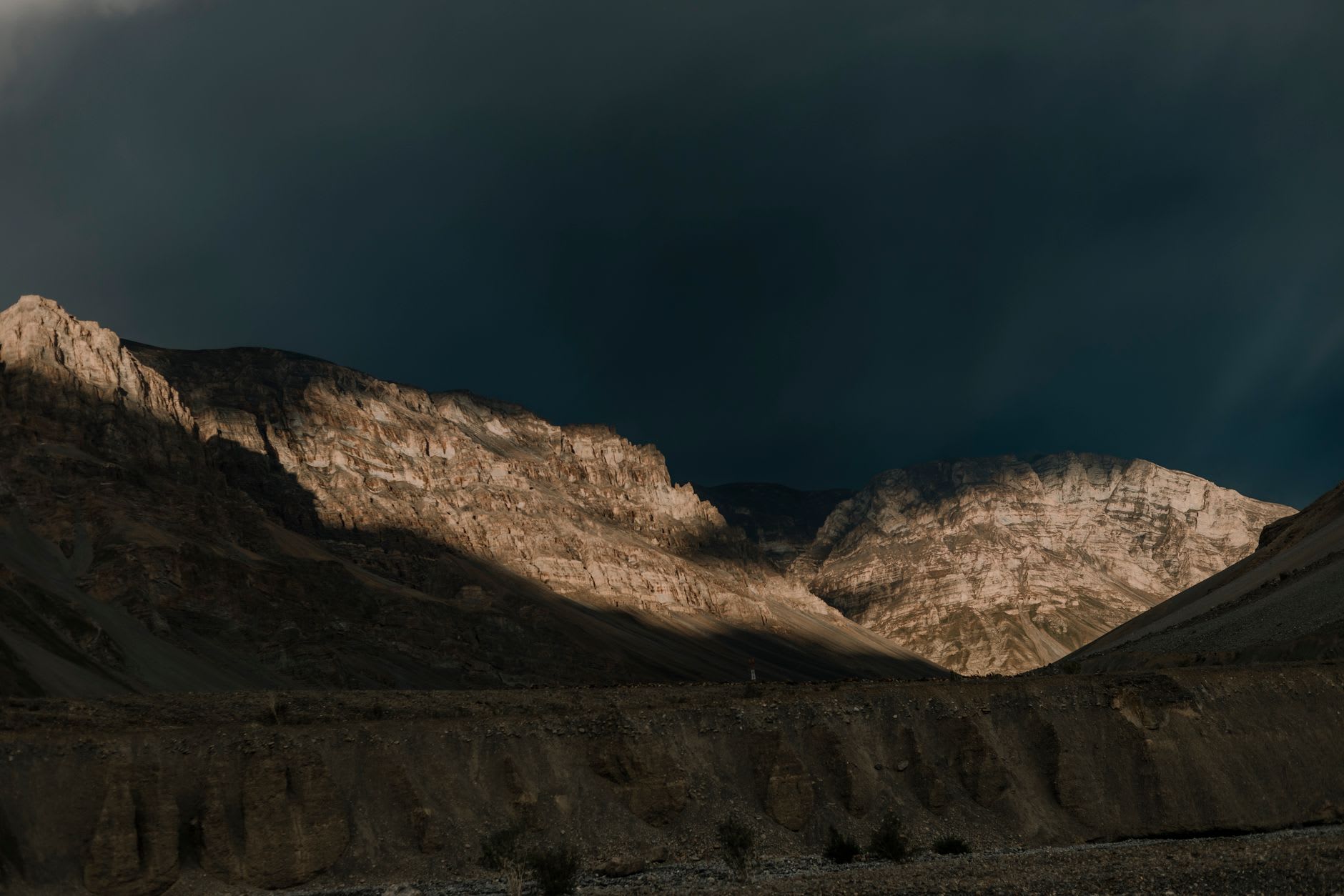 Des grappes de maisons blanchies à la chaux perchées sur un éperon rocheux au-dessus de la rivière Spiti avec des sommets enneigés en arrière-plan