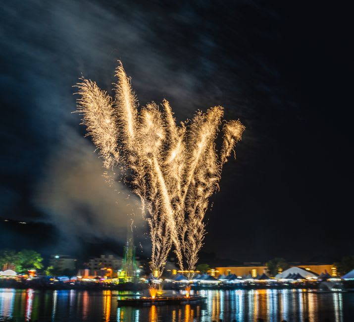 Nightly fireworks reflected on the still surface of Lake Toya, seen from the lakeside promenade at Toyako Onsen