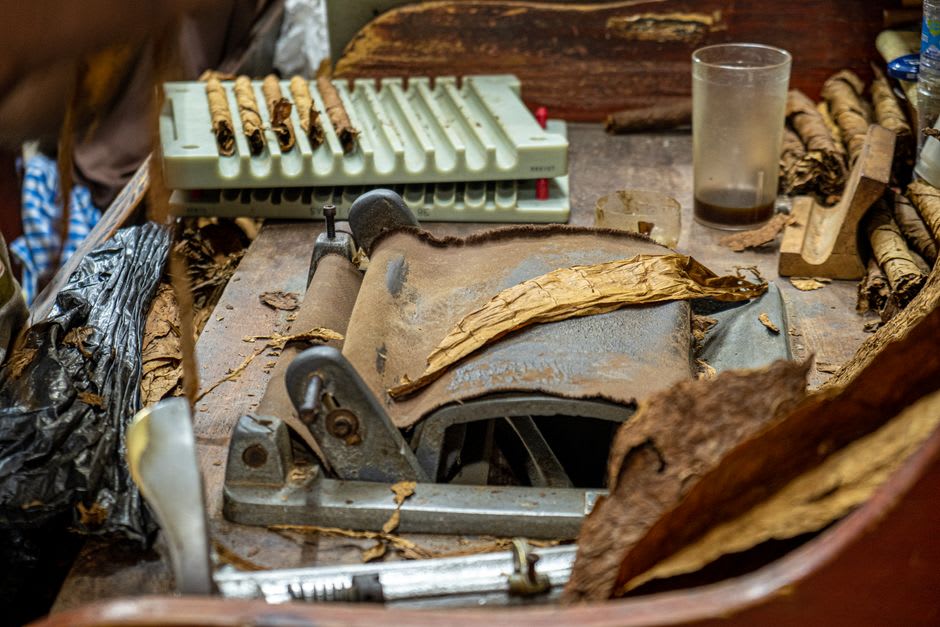 A cigar roller's hands shaping tobacco leaves at a factory table in Santa Rosa de Copán