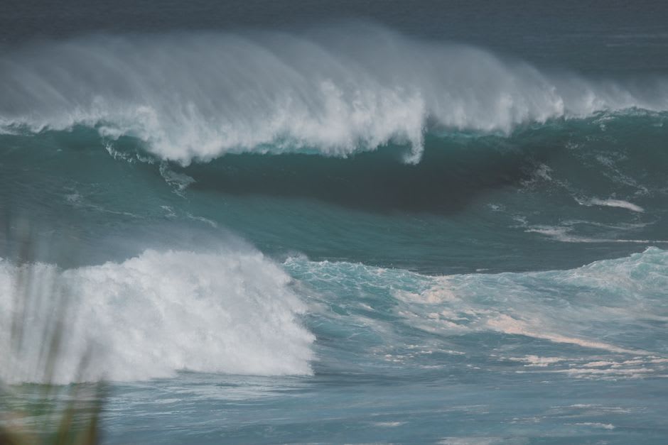 Big Wave Bay a la hora dorada, surfistas en siluetas sobre el agua y la playa casi vacía