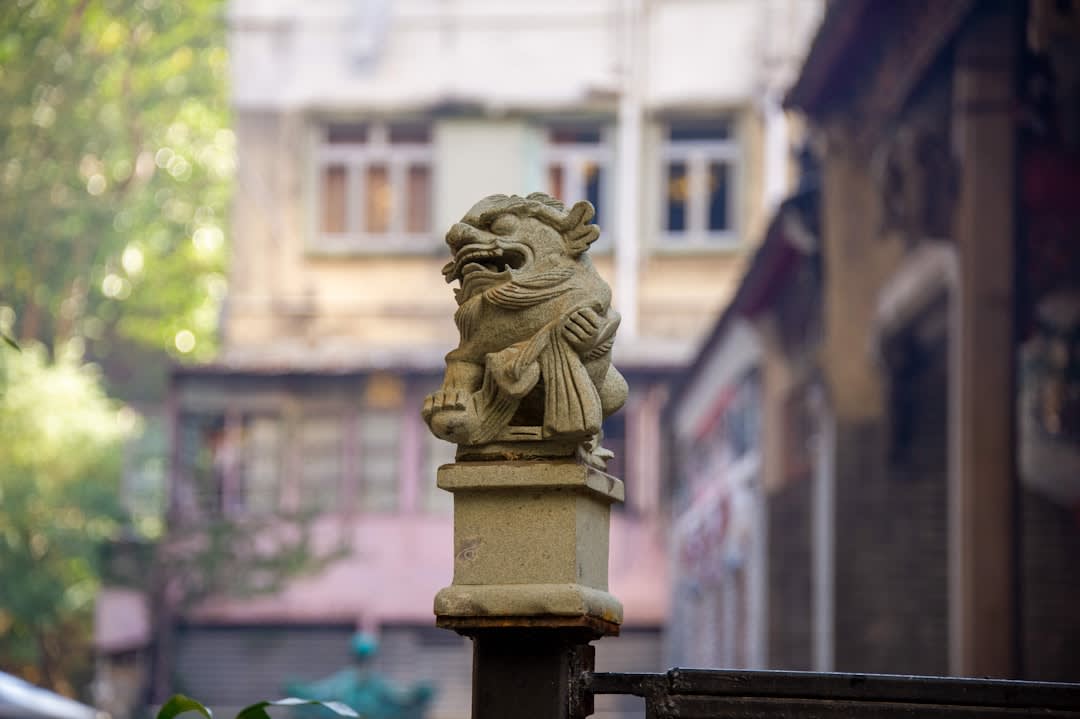 Una estatua de león de piedra desgastada en la puerta de entrada del templo, con la calle estrecha de Stone Nullah Lane visible detrás