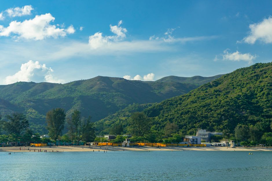 Velas de windsurf aparejadas a lo largo de la Playa de Sha Ha en Sai Kung, tablas tendidas en la arena listas para el lanzamiento