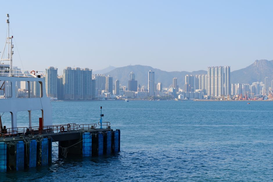 Un practicante de windsurf trazando una línea por Port Shelter cerca de la Playa de Sha Ha, con las colinas de Sai Kung visibles detrás