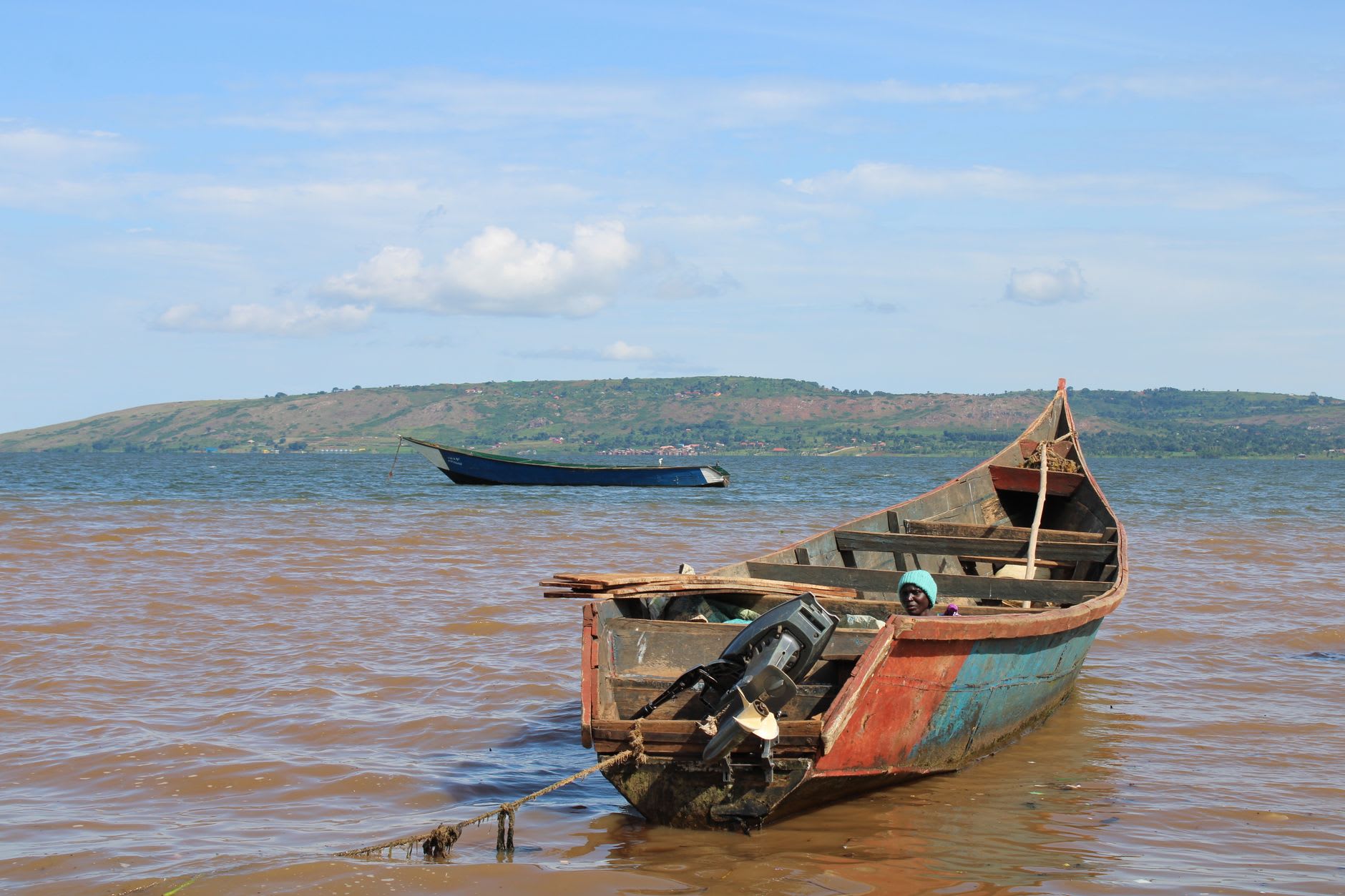 The jade-green surface of Lake Turkana seen from the black volcanic shoreline, the distant mountains of the Ethiopian border just visible through the heat haze